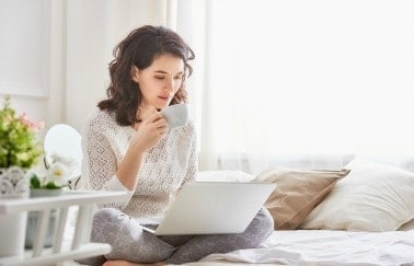 Woman enjoys coffee while reading about license reciprocity in real estate