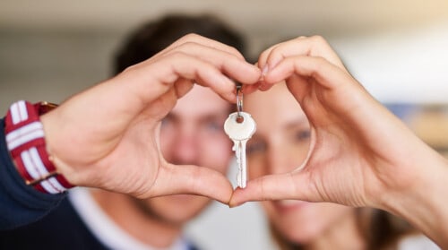Portrait of a happy young couple proudly displaying the keys to their new house