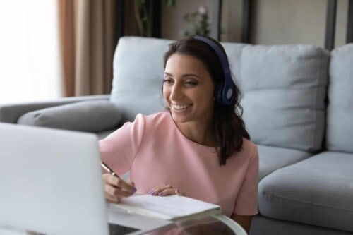 Happy woman in headphones enjoying online education.