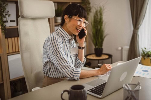 A real estate agent working for an online real estate brokerage looks at computer and talks on phone.